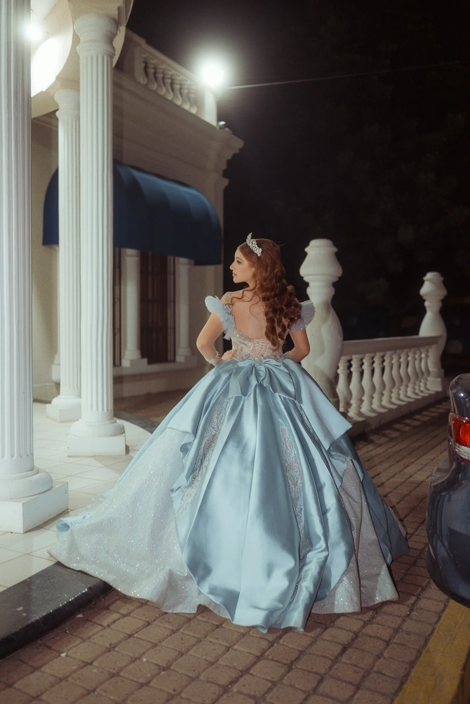 Robe de bal bleu clair vue de dos, en extérieur le soir