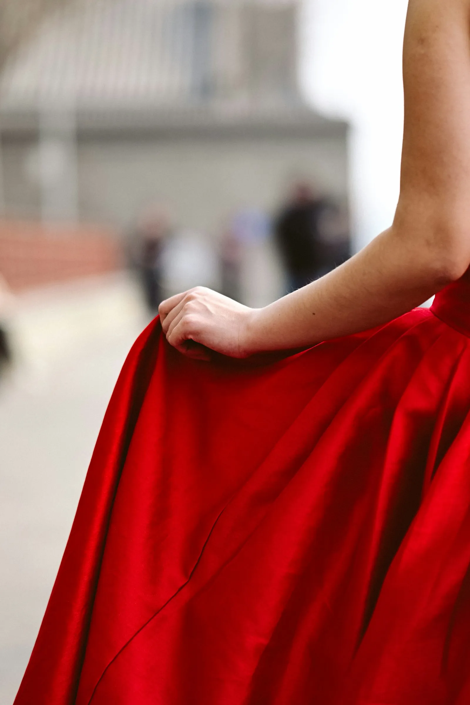 Détail : drapé de satin rouge tenu à la main